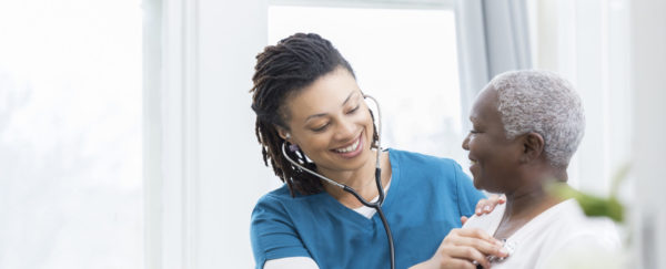 A nurse taking the pulse of an older woman.